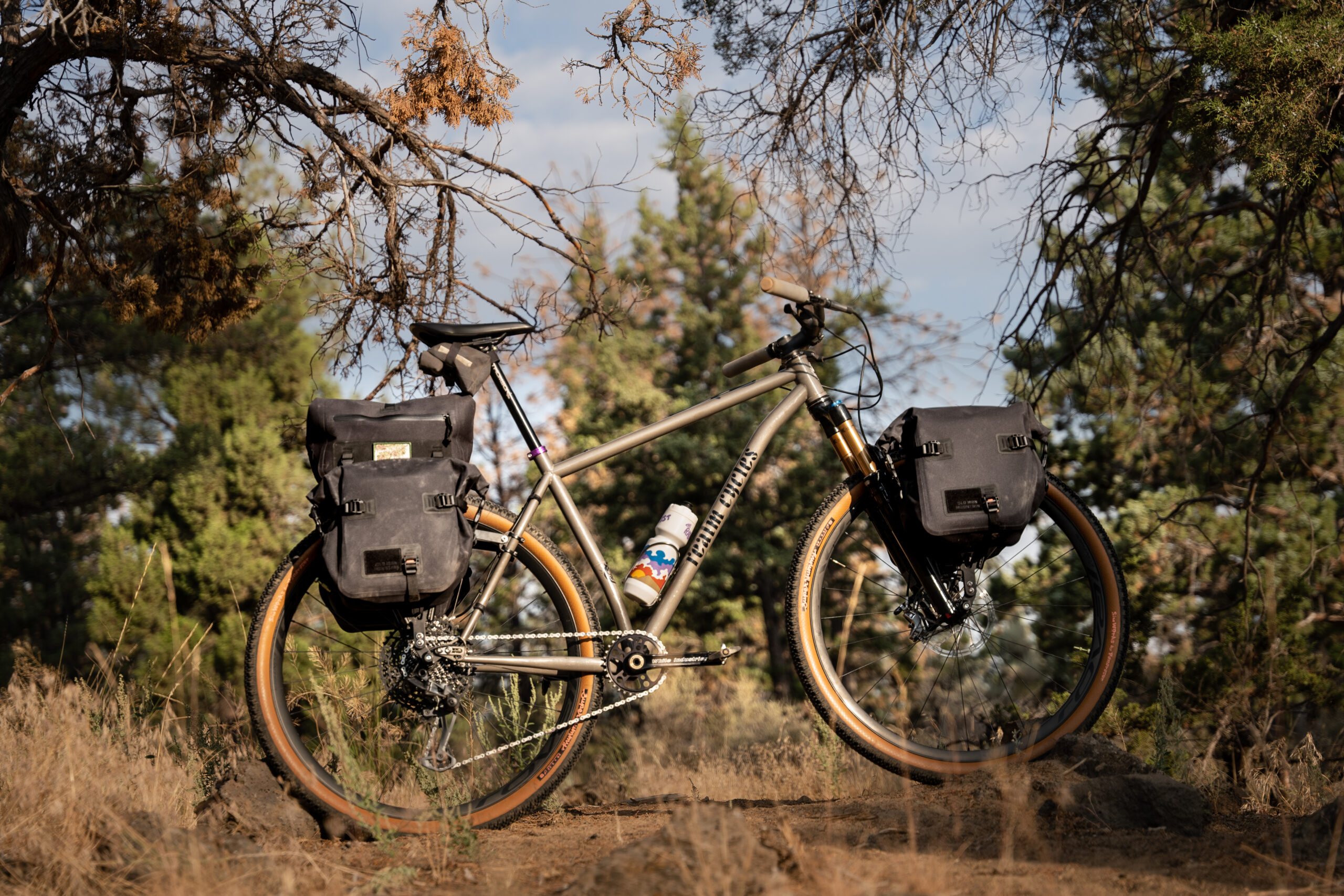 Realm Cycles hardtail mountain bike with a front and rear bike rack. On the front rack is a Juniper Trunk bag, and on the rear rack is a pair of Ponderosa Panniers.