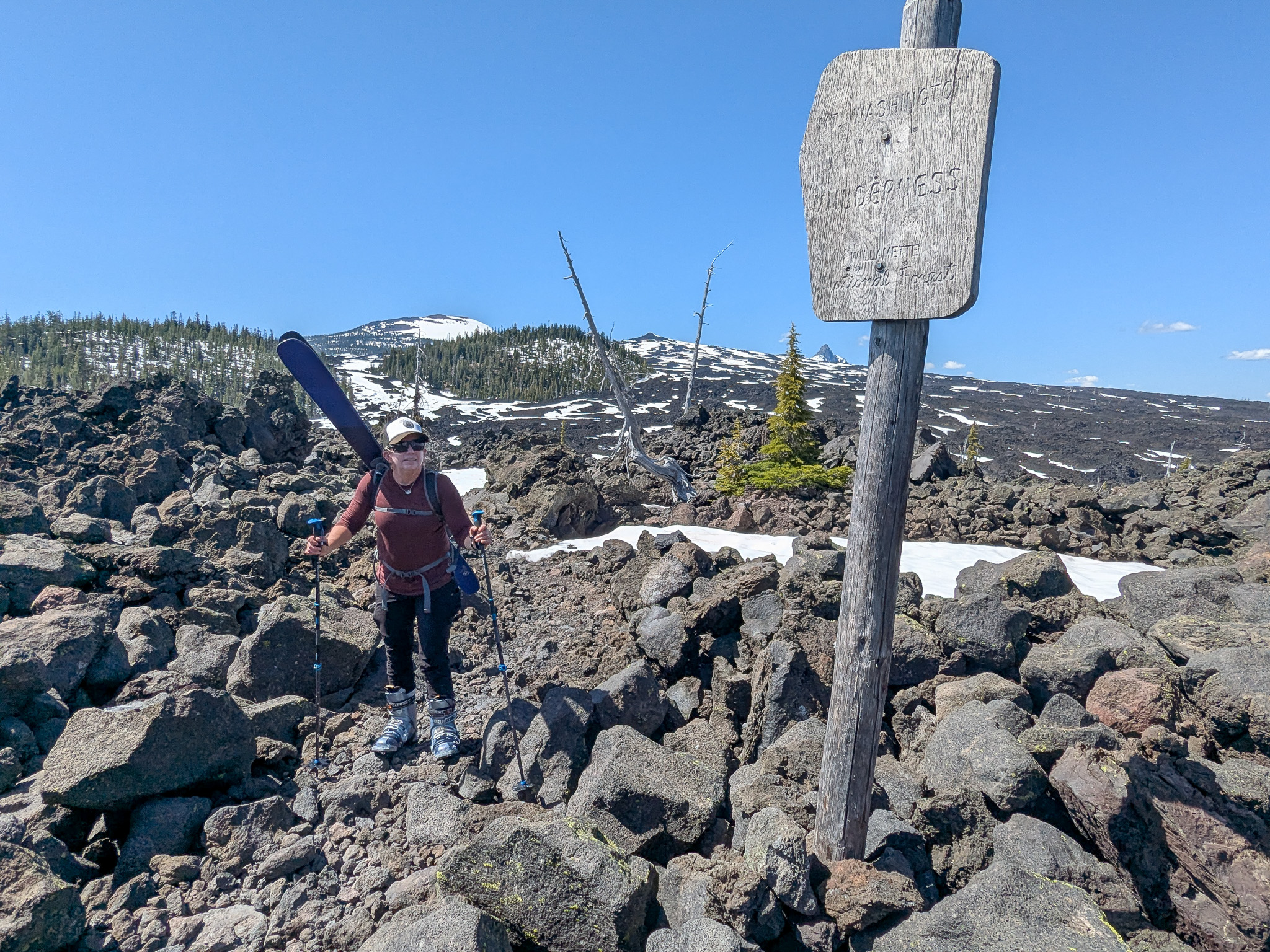 Katy hiking through lava field carrying her skis.