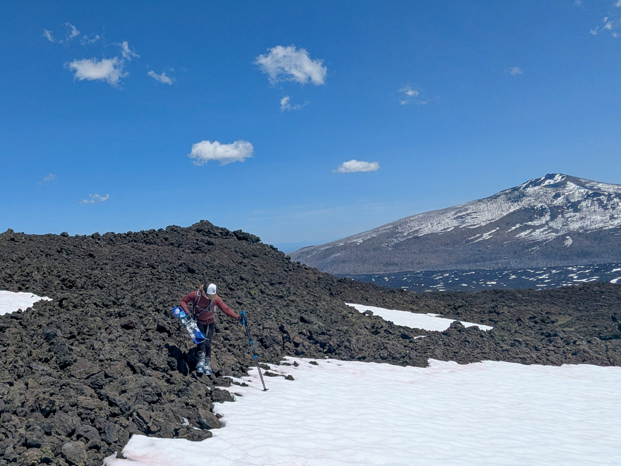 Katy climbing down onto a snow field from lava rocks.