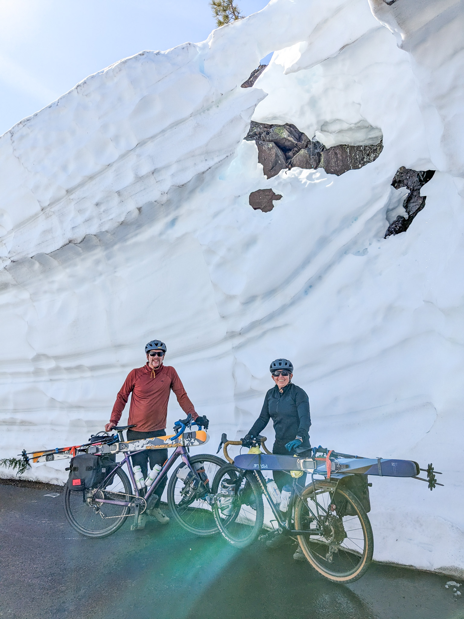 Bike-ski-Chris-Katy-5 Chris and Katy standing with their bikes in front of a snow bank.