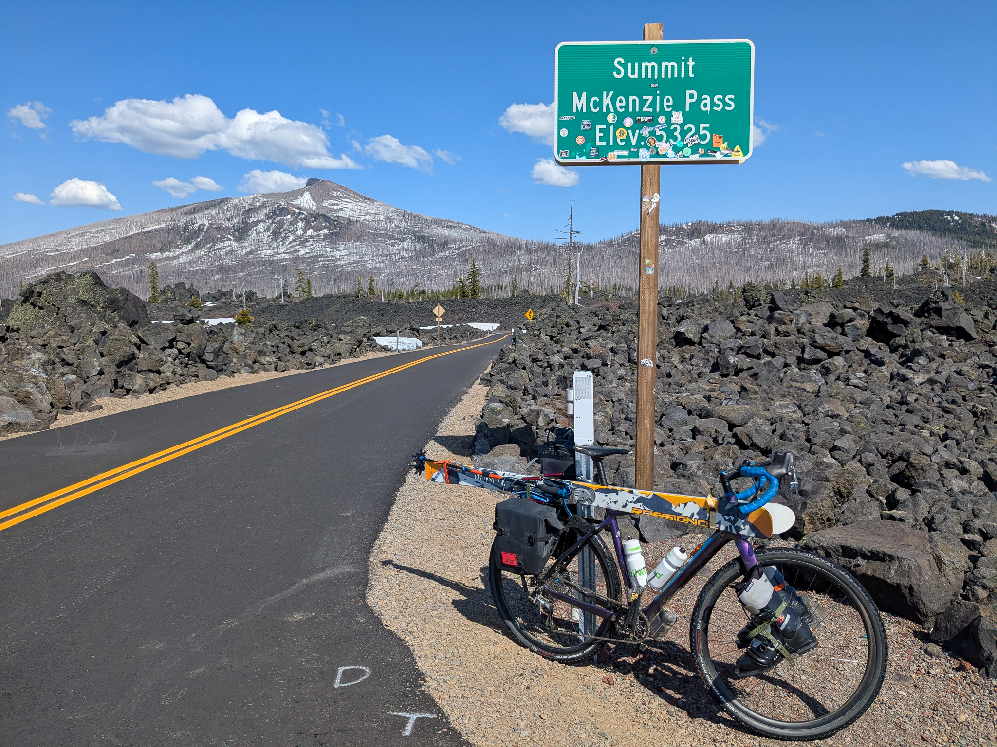 Chris's bike leaning against McKenzie Pass Summit roadsign.