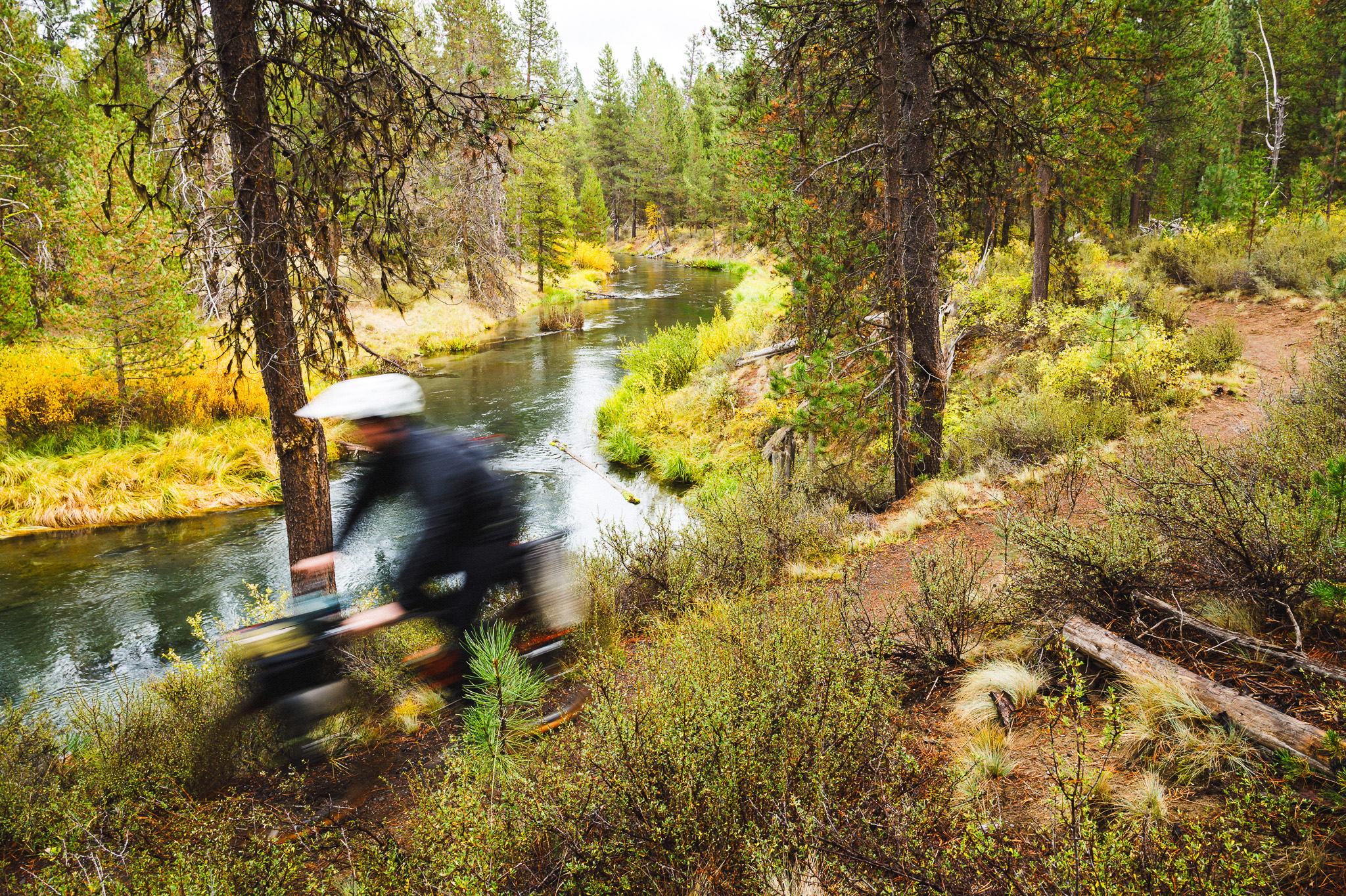 _Q9A9144 Motion-blurred cyclist riding along a river bikefishing.