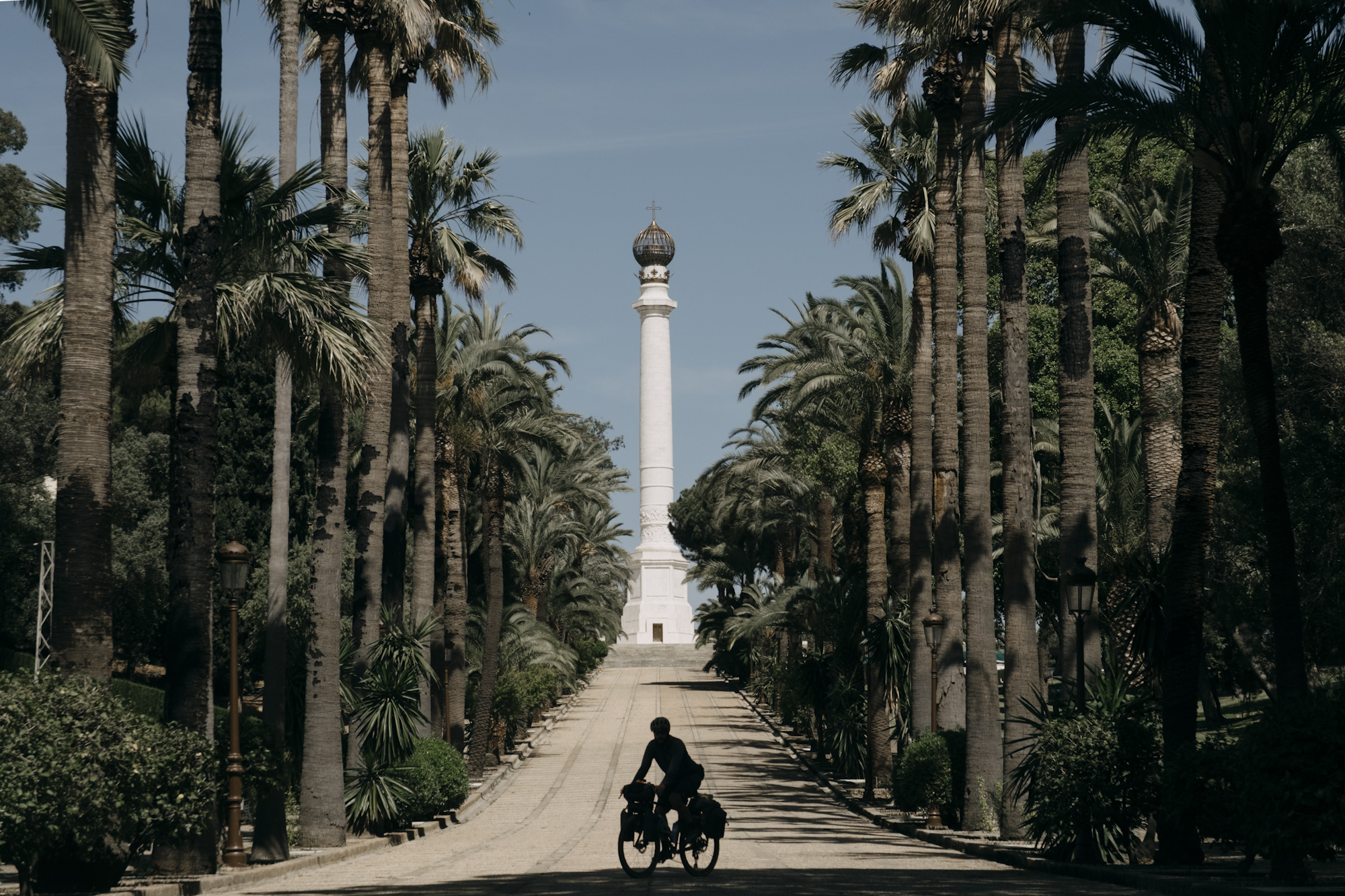 Angustias_Tour_TomasMontes-04 Silhouette of Javi pedaling towards a temple.