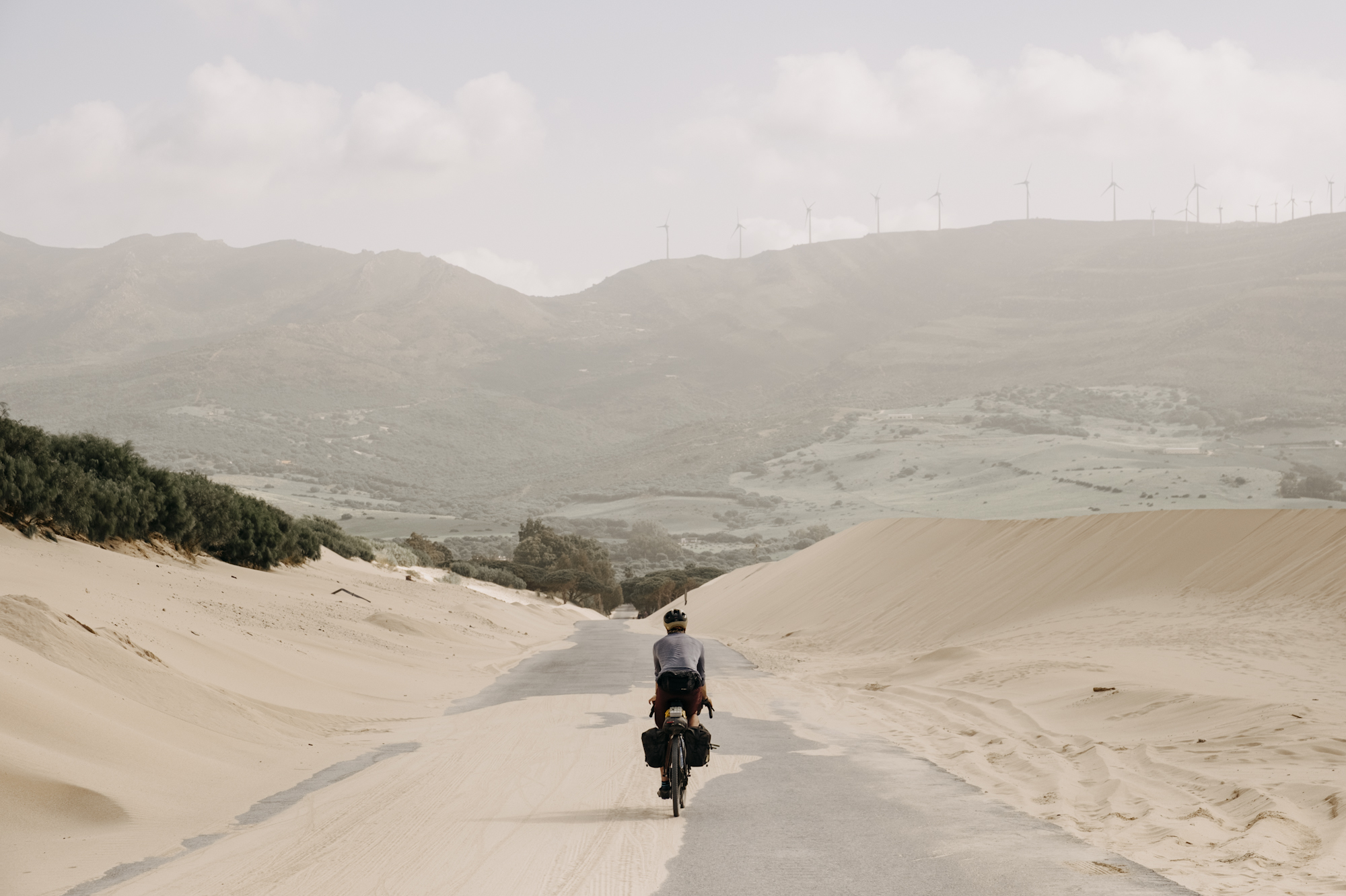 Angustias_Tour_TomasMontes-53 Pedaling along a paved, sand covered road through sand dunes.