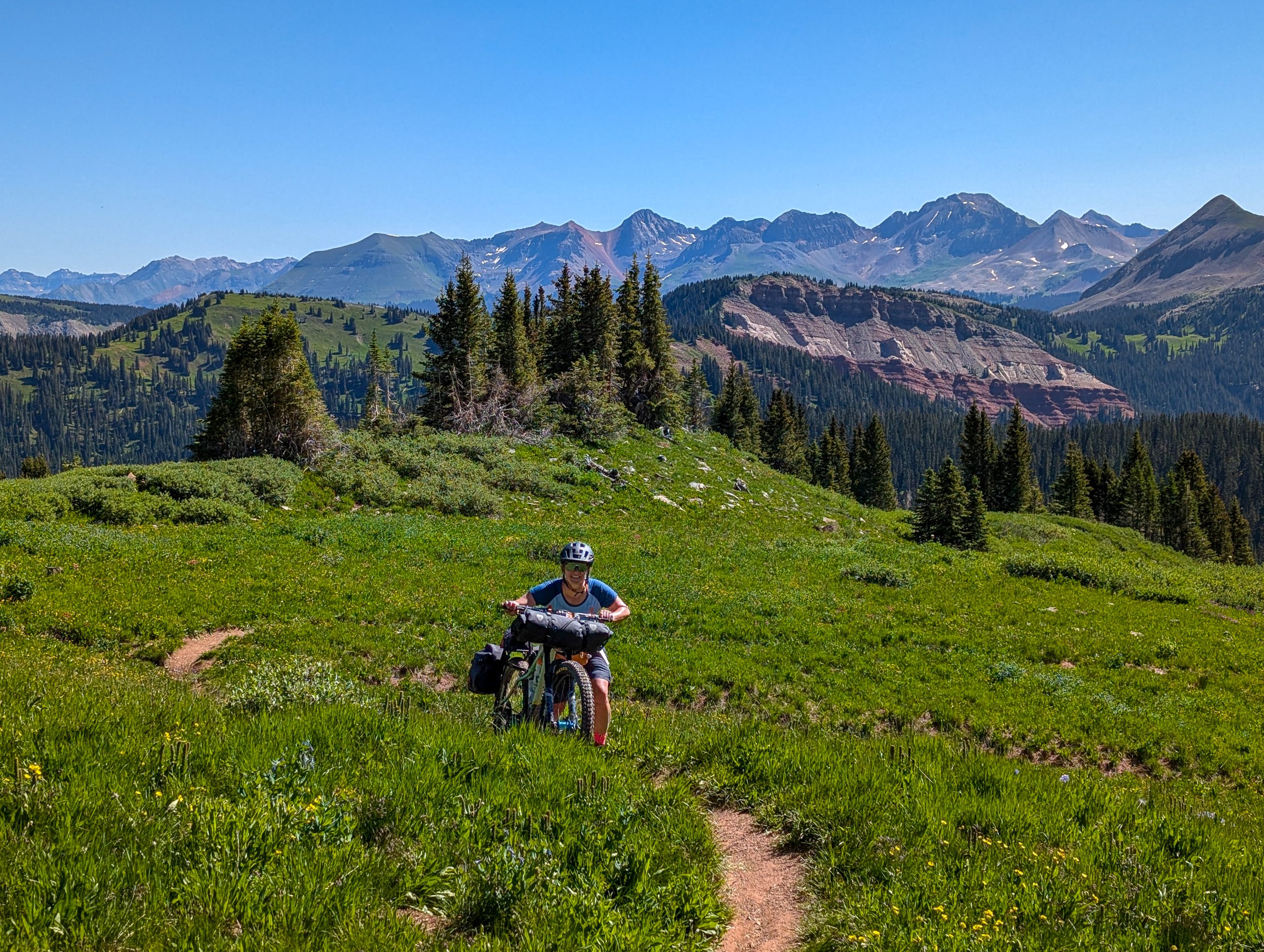 Samantha pushing her bikepacking bike up a steep trail in the Colorado Alpine.