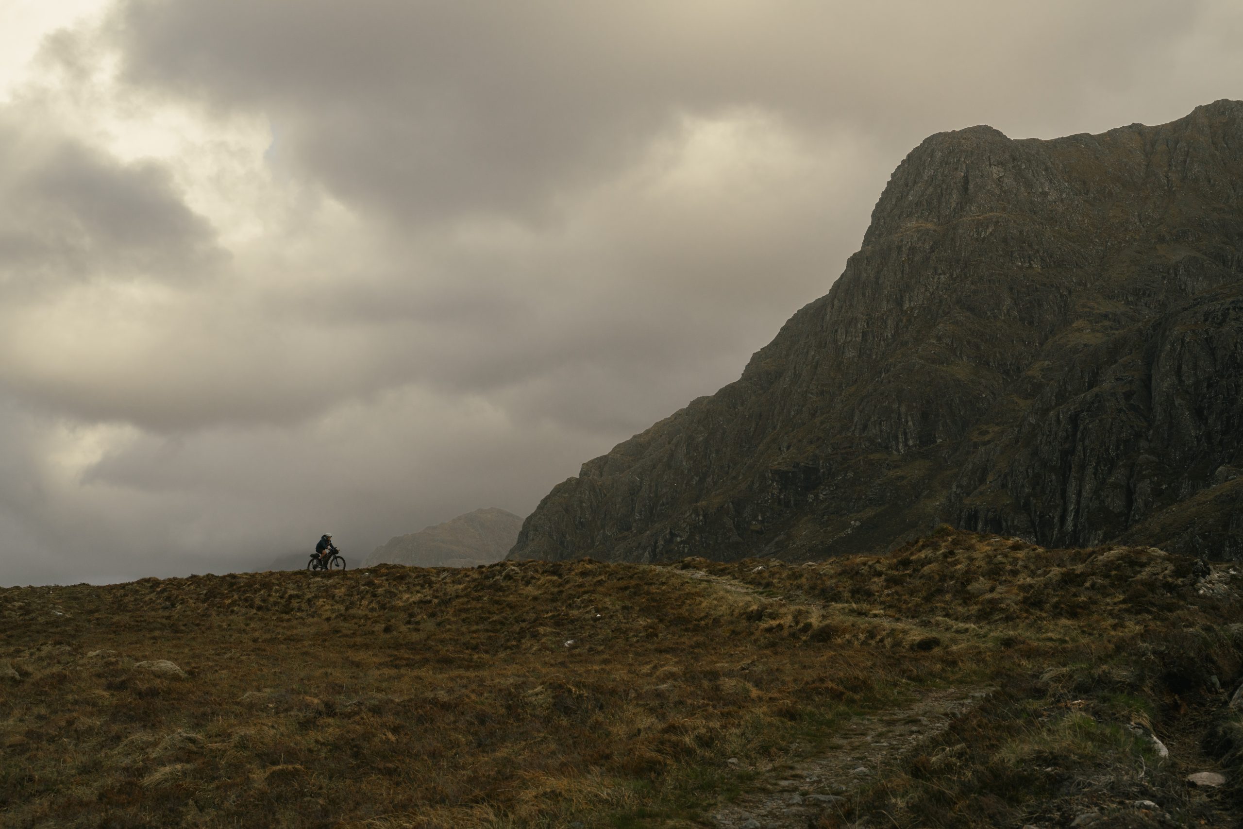 GR506356 Hannah silhouetted on her bike against a dramatic landscape.